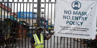 A security man stands at the main gate of a Lagos market to prevent access in compliance with Covid-19 measures.