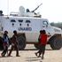 Children walk past a vehicle of the United Nations and African Union peacekeeping mission in South Darfur in December 2020.