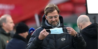 Liverpool manager Jurgen Klopp replaces his protective face mask