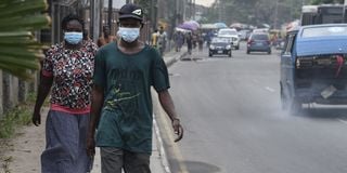 People walk along a main road wearing face masks in Lagos in February 2020.