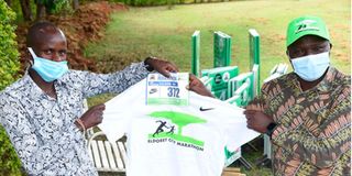 Eldoret Marathon race director Moses Tanui (right) gives Mark Rotich his bib