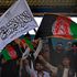 Spectators wave Afghanistan's and Taliban flags as they watch the Twenty20 cricket trial match 