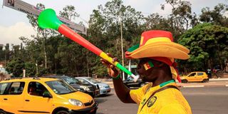 A vendor blows on a vuvuzela while selling Cameroon football attire in Yaounde 