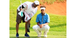 Njoroge Kibugu lines up his putt at the 18th hole green with his caddie Bo Ciera during Magical Kenya Open