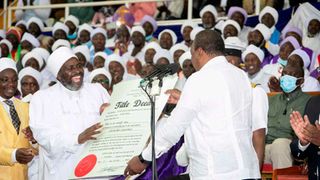 President Uhuru Kenyatta presents a title deed to the Akorino faithful