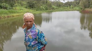 An elderly woman stands near Shiranga dam