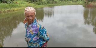 An elderly woman stands near Shiranga dam