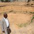 Maina Mugo stands in front of a dry water pan at Solio Settlement Scheme