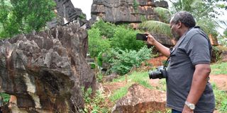 A local tourist takes a photo of the black rock at Chasimba Caves in Kilifi County.