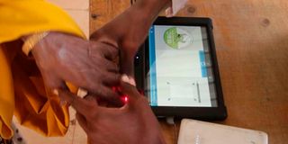 A polling clerk uses a Kiems kit to identify a voter at Wajir Girls High School.