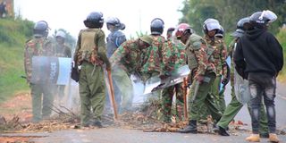 Anti-riot police remove boulders placed on the road by protesters along Kisii - Kilgoris road.