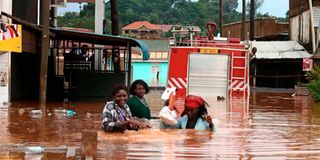 Ugandan residents cross a flooded street in Entebbe 