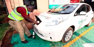 Bernard Wasike an electrical engineer at Chargenet Kenya plugs in a car at an EV charging station.
