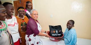 First Lady Margaret Kenyatta hands over a dignity bag to obstetric fistula survivor Suzanne Sikwar.