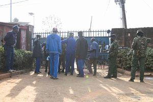 Police officers close the gate after polls closed during Kenya's general election at the Olympic High polling station.