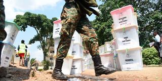 National Youth Service officer walking past ballot boxes containing ballot papers for Kanduyi constituency.