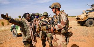 Malian soldier gestures as he talks to a French soldier 
