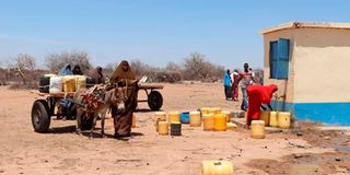 Isnina Abass, a resident of Ahmed Tukalo Village pulls a cart close to a water point 