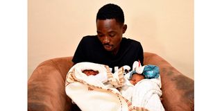 Robert Omondi holds his newborn twin boys