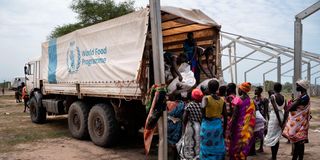 Women unload bags of sorghum from a WFP truck 