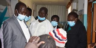 Baringo Governor Benjamin Cheboi (in grey suit) talking to a patient while on an inspection tour of Eldama Ravine hospital