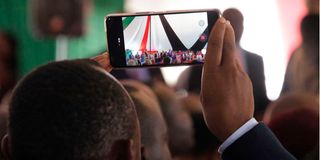 A man uses his phone to record proceedings during a past function. 