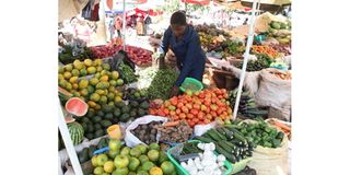 A trader sorts tomatoes at her stand at Chaka market in Nyeri County.