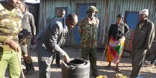 Security officials inspect containers used to store illicit brews during a raid by police in Isiolo 