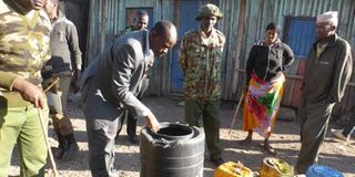 Security officials inspect containers used to store illicit brews during a raid by police in Isiolo 