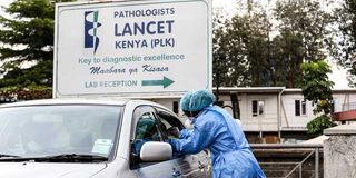 A health worker at Lancet Kenya collects samples for testing Covid-19 from a motorist 