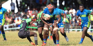 KCB's Davis Chenge charges past Daniel Angwech of Kabras Sugar