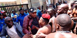 Comedian Eric Omondi (right) struggles with police officers in an attempt to force his way into Parliament Buildings in Nairobi