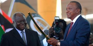 Kenya's fourth president Uhuru Kenyatta receives a sword as a symbol of authority from his predecessor Mwai Kibaki 
