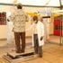 A medic helps a resident onto the platform of a digital x-ray machine during a Tuberculosis screening drive in Kisumu County