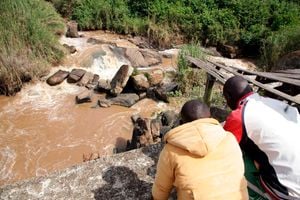 Residents look at an unidentified body that was floating in River Yala