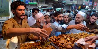 Muslim devotees crowd to buy food in a market on the first day of the holy fasting month of Ramadan in Peshawar