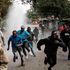 Protesters run away from water released by a police’s water cannon vehicle during a mass rally in Kibera