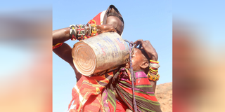 A woman gives water to her child from a tin in Manguto village in North Horr, Marsabit County. 