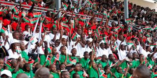 School children wave Kenyan flags during the 60th Madaraka Day celebrations at Moi Stadium in Embu