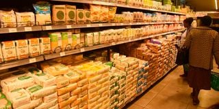 Customers countercheck the prices of maize flour at a supermarket in Nakuru City