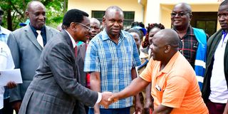 Siaya Governor James Orengo hands feed to a fish farmer