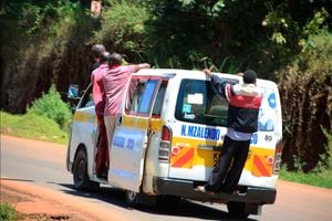Four men precariously hang on a moving matatu