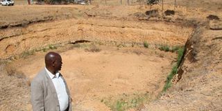 Maina Mugo stands in front of a dry water pan at Solio Settlement Scheme